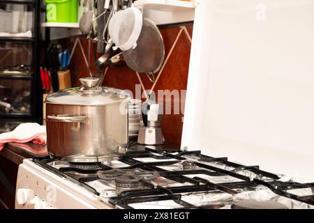 A white stove top with a pot on it. The pot is filled with water and is boiling Stock Photo