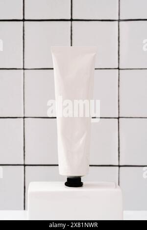 White metal cream tube mockup for care products in bathroom, spa, cream, gel, mask for face on white marble shelf and wall tiles. Front view. Product Stock Photo