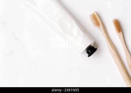 Top view of white metal tube without label and toothbrushes on white background. Mockup scene for cosmetic, toothcare Copy space. Flat lay Stock Photo