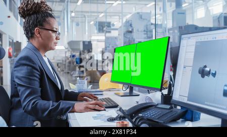 Factory Office Room: Industrial Engineers Developing Models of a Heavy Industry Machine Parts on a Computer 3D Software. One Computer Monitor Display is a Green Screen Mock Up Template. Stock Photo
