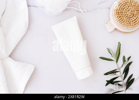 Flat lay of white plastic bottle without label, wooden brush, sponge for body and towel on white bath marble background. Minimal concept Stock Photo