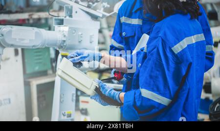 Engineers team mechanic using computer controller Robotic arm for welding steel in steel factory workshop. Industry robot programming software for aut Stock Photo