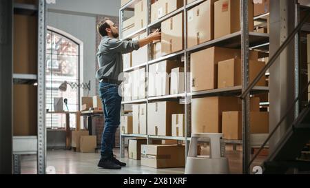 Warehouse Inventory Manager Using Smartphone to Scan a Shipment Details on Parcel, Preparing a Small Cardboard Box for Postage. Stylish Male Small Business Owner Working in Storeroom. Stock Photo