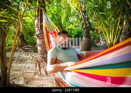 man working on laptop on exotic beach Stock Photo