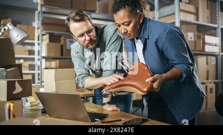 Happy Male and Female Working in Warehouse. Talking, Using Laptop Computer, Checking Retail Stock, Preparing Shipment with a Stylish Retro Bicycle Seat. Successful Storeroom Workers Enjoying Work. Stock Photo