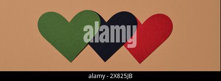 three hearts with the colors of the black liberation flag, green, black and red, on a brown background, in a panoramic format to use as web banner Stock Photo