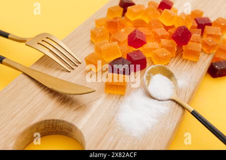Yummy candied fruit jelly on a wooden plate with spoon, fork and knife Stock Photo