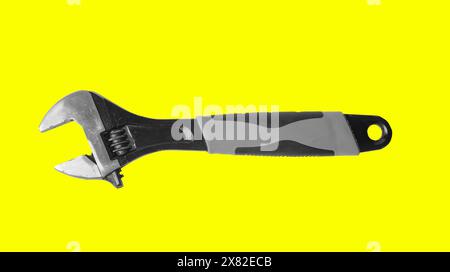 Mechanic with wrench, adjustable spanner in hand on yellow background. Old steel tools, mechanical repair and service. Professional equipment for indu Stock Photo