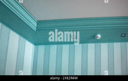 Part of the living room, corner of the wall from the ceiling, mounted LED lights in a wooden console on the ceiling, blue tinting Stock Photo