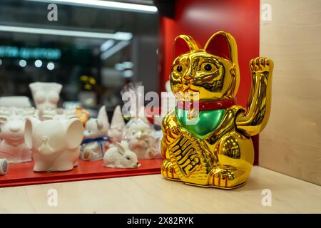 Maneki Neko, Japanese Lucky Cat in a gift shop window. Golden cat brings good luck and wealth closeup Stock Photo