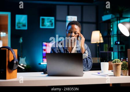 Stressed and frustrated black woman working from home reading reports and documents. Tired, sad overworked and depressed freelancer having a headache, troubled with anxiety and mental health. Stock Photo