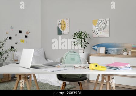 Student's table with laptop and copybooks in bedroom Stock Photo