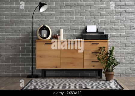 Modern printer and coffee machine on commode near grey brick wall in office Stock Photo