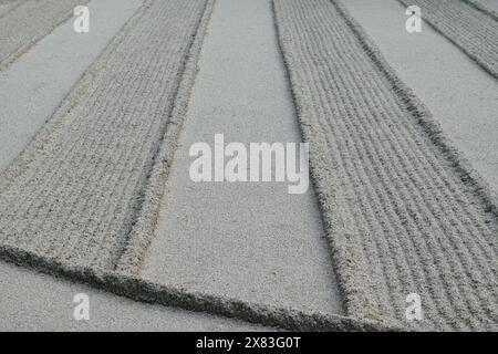 Close-up of a zen garden with meticulously raked sand creating parallel lines and patterns. Stock Photo