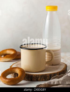 Traditional boiled milk in a beige enamel mug with a pretzel and a plastic bottle Stock Photo