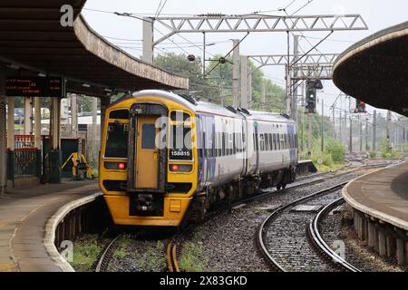 Northern trains express sprinter diesel multiple unit train number 158815 preparing to leave Carnforth station platform 1 on 22 May 2024 in rain. Stock Photo