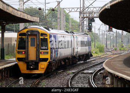 Northern trains express sprinter diesel multiple unit train number 158815 leaving Carnforth station platform 1 on 22 May 2024 in pouring rain. Stock Photo