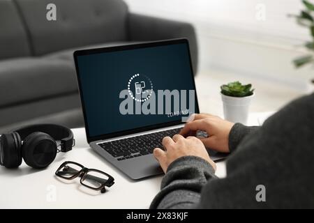Loading screen displaying progress. Man working on laptop at table indoors, closeup Stock Photo