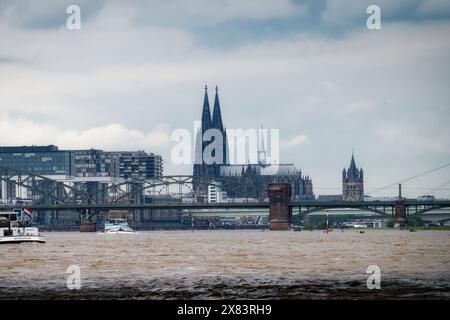 cologne, germany may 22 2024: cargo ships pass through cologne on the muddy brown flood waters of the rhine Stock Photo