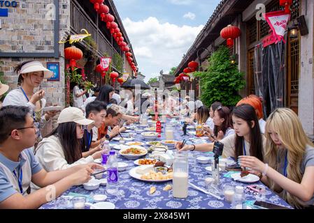 NINGBO, CHINA - MAY 19, 2024 - Tourists taste food at the long table banquet in Qiantong Ancient Town in Ningbo, Zhejiang province, China, May 19, 202 Stock Photo