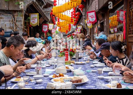 NINGBO, CHINA - MAY 19, 2024 - Tourists taste food at the long table banquet in Qiantong Ancient Town in Ningbo, Zhejiang province, China, May 19, 202 Stock Photo