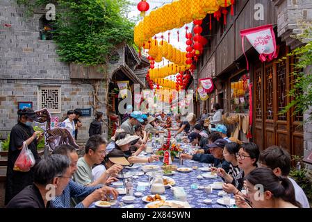 NINGBO, CHINA - MAY 19, 2024 - Tourists taste food at the long table banquet in Qiantong Ancient Town in Ningbo, Zhejiang province, China, May 19, 202 Stock Photo