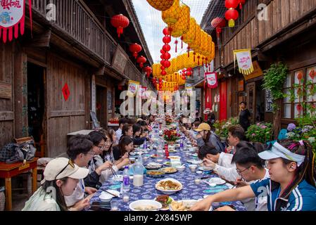 NINGBO, CHINA - MAY 19, 2024 - Tourists taste food at the long table banquet in Qiantong Ancient Town in Ningbo, Zhejiang province, China, May 19, 202 Stock Photo