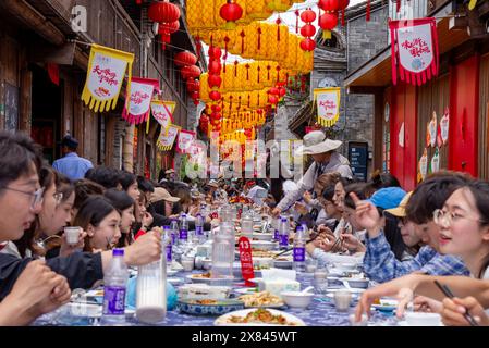 NINGBO, CHINA - MAY 19, 2024 - Tourists taste food at the long table banquet in Qiantong Ancient Town in Ningbo, Zhejiang province, China, May 19, 202 Stock Photo