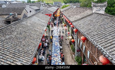 NINGBO, CHINA - MAY 19, 2024 - Tourists taste food at the long table banquet in Qiantong Ancient Town in Ningbo, Zhejiang province, China, May 19, 202 Stock Photo