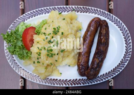 Two Nuremberg sausages with potato salad on an oval plate in a garden restaurant, Bavaria, Germany Stock Photo