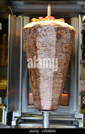 Large piece of kebab meat on a spit, topped with tomatoes, in a fast food restaurant, Istanbul, Istanbul province, Turkey Stock Photo