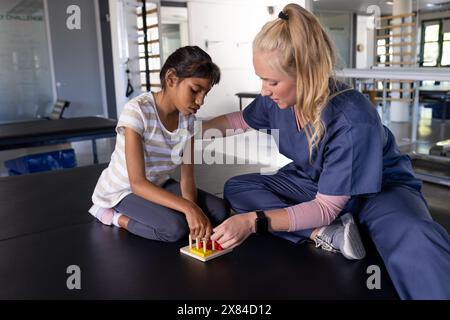 At rehabilitation center, Caucasian female therapist treating biracial girl with cerebral palsy Stock Photo