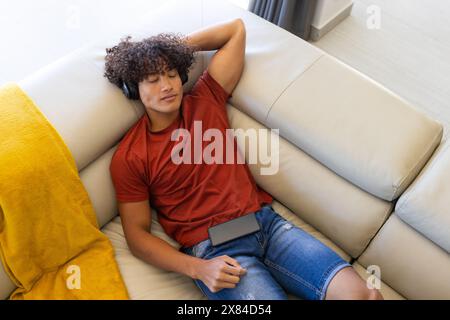 A biracial young male wearing headphones, relaxing at home Stock Photo