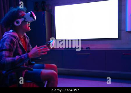 A biracial young male at home, wearing headphones, playing virtual reality games, copy space Stock Photo