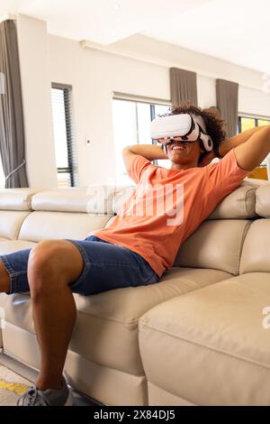 A biracial young male wearing VR headset, relaxing at home Stock Photo