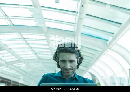 Portrait of one young latin American Caucasian man working on a computer laptop inside and airport. Stock Photo