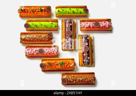 Variety of colorful eclairs with exquisite toppings on white background Stock Photo
