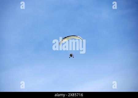 A Powered Motorized paraglider flying against the blue sky outdoor activity, extreme sports, sport of paragliding Stock Photo