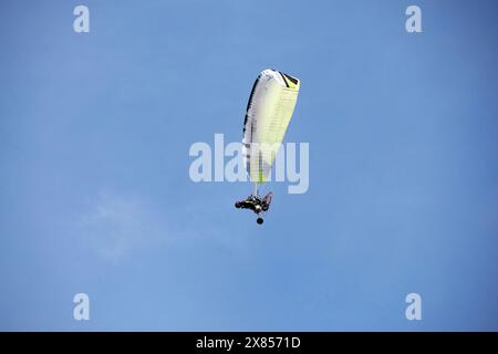 A Powered Motorized paraglider flying against the blue sky outdoor activity, extreme sports, sport of paragliding Stock Photo