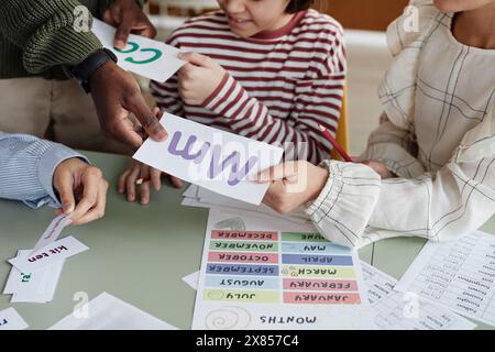 High angle view of unrecognizable foreign language teacher giving printouts to students during lesson Stock Photo
