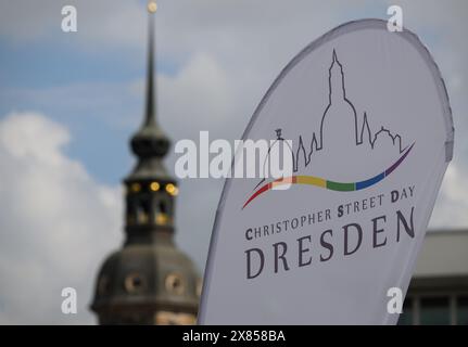 23 May 2024, Saxony, Dresden: A flag with the logo and the inscription 'Christopher Street Day Dresden' flies in the wind during the presentation of a rainbow-colored bus of the Dresdner Verkehrsbetriebe (DVB) on the Altmarkt, the Hausmannsturm can be seen in the background. On the occasion of this year's Christopher Street Day, a so-called rainbow bus is being presented on the Altmarkt. This is intended to enable people with disabilities to participate in the demonstration in a self-determined way. This year's Christopher Street Day in Dresden will take place from May 25 to June 10, 2024. Pho Stock Photo