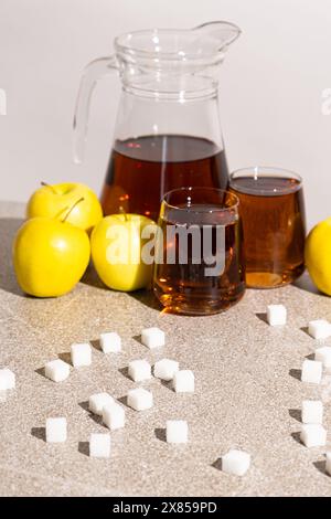 Sugar content in fruit juices. Sugar cubes and glasses of apple juice. Stock Photo