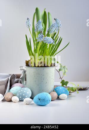 Easter eggs and light blue muscari flowers in cup on a white table. Easter still life Stock Photo
