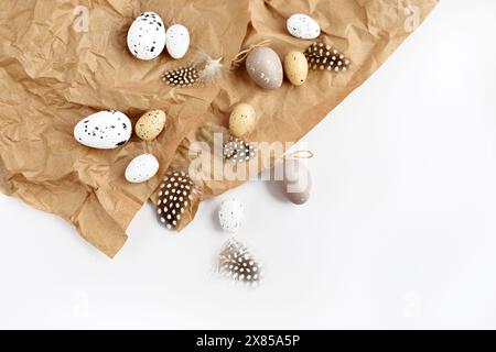 Easter eggs and feathers on a brown kraft paper background on a white table. Top view. For easter greeting cards with copy space. Stock Photo