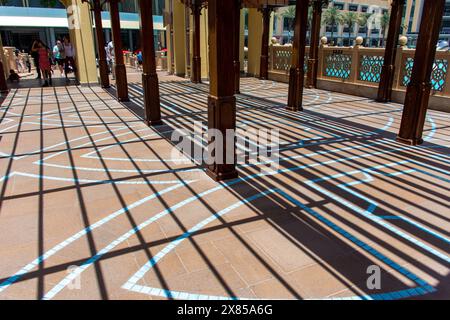 Dramatic shadows cast by a pergola on a tiled walkway leading to Souk Al Bahar in Dubai, UAE. Stock Photo