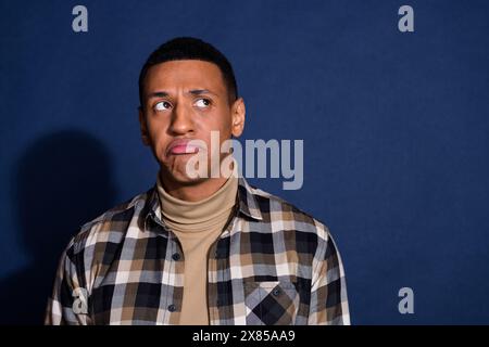 Photo portrait of nice young man look empty space moody wear trendy plaid outfit isolated on dark blue color background Stock Photo