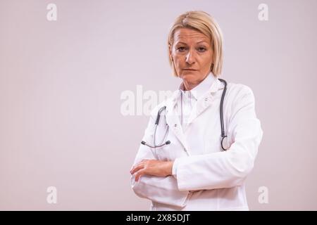 Portrait of angry mature female doctor  on gray background. Stock Photo