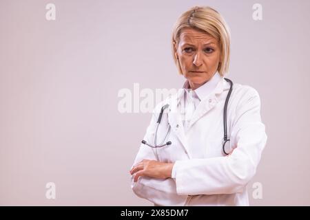 Portrait of angry mature female doctor  on gray background. Stock Photo