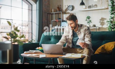 Happy Accounting at Home: Cheerful Smiling Man Using Laptop Computer, Filling Tax Forms. Businessman Solving All His Paperwork Problems: Bills, Invoices, Budget Surplus, Has Financial Success Stock Photo