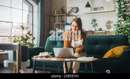Happy Accounting at Home: Cheerful Smiling Woman Using Laptop Computer, Filling Tax Forms. Businesswoman Solving All His Paperwork Problems, Finishes the Job: Bills, Invoices, Has Financial Success Stock Photo